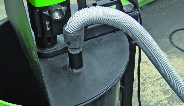 A vacuum hose attached to a black circular base with a green and black component above.